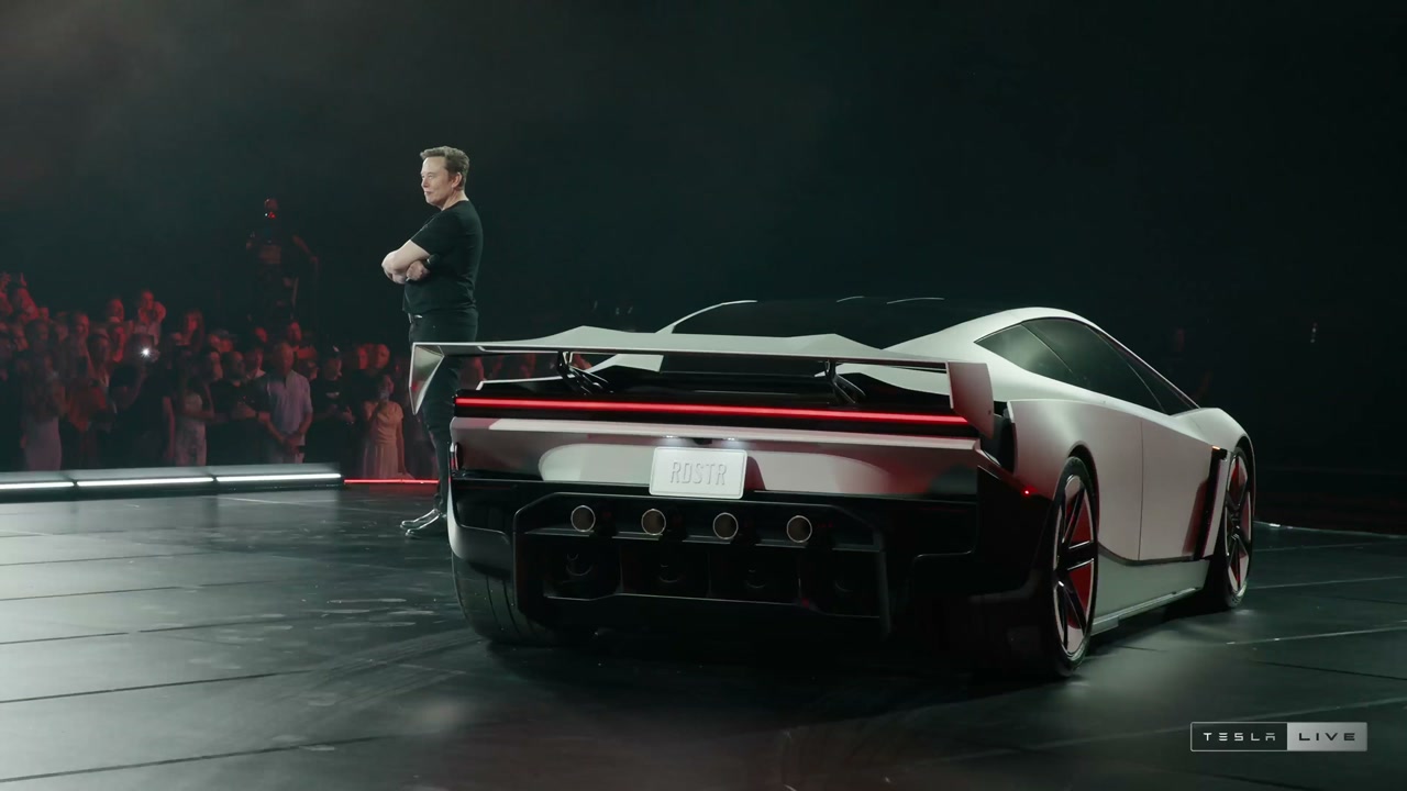 The real white Roadster on stage at the October 2026 unveiling, viewed from the rear with its wing deployed